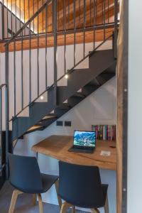 a wooden table with chairs and a laptop on it under a staircase at Chalet Grifone - Chalet Maso Vecchio nel cuore del Lagorai Trentino in Castello Tesino