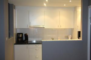 uma cozinha com armários brancos e uma pia em Mirage em Ostend