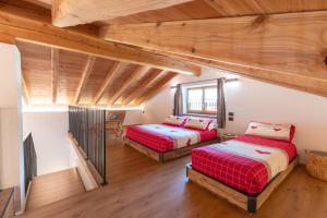 two beds in a room with wooden ceilings at Chalet Grifone - Chalet Maso Vecchio nel cuore del Lagorai Trentino in Castello Tesino