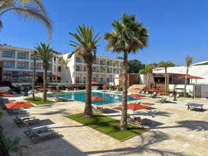 a resort with a pool and palm trees and chairs at Grand Dominium in Agadir