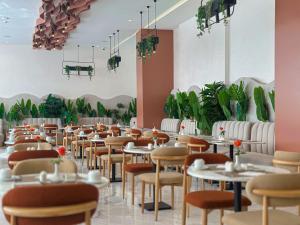 a dining room with tables and chairs and plants at Grand Dominium in Agadir