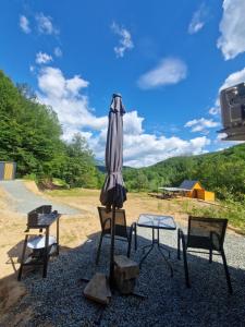 a table and two chairs and an umbrella on a gravel road at Firiza Nature Lodges in Baia Mare