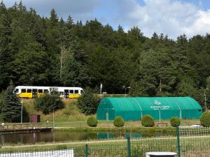 a white bus and a green tent next to a lake at Apartament Snooze in Jedlina-Zdrój