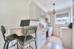 a kitchen with white cabinets and a table and chairs at Chic Flat Hideaway with Private Courtyard - Pass the Keys in Guildford +19 photos