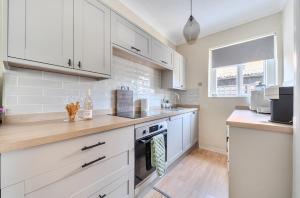 a kitchen with white cabinets and a stove top oven at Chic Flat Hideaway with Private Courtyard - Pass the Keys in Guildford