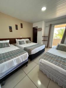 a hotel room with two beds and a window at Pousada e Restaurante Império do Marisco in Maragogi