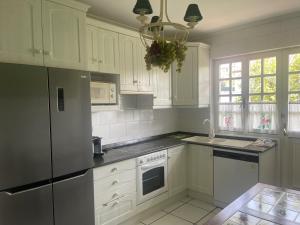 a kitchen with white cabinets and a stainless steel refrigerator at Casa Sierrapando - by Wehomes in Torrelavega