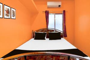 a bed in a room with an orange wall at Capital O Sri Krishna Palace Near Sum Hospital in Durgāpur +21 photos
