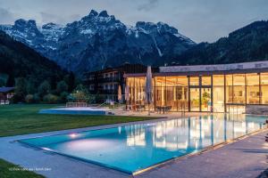 a building with a swimming pool in front of mountains at JUFA Hotel Werfenweng in Werfenweng