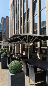 a table and chairs with an umbrella in front of a building at guestified GRAND AIRPORT Hotel Düsseldorf Ratingen in Ratingen