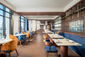 a restaurant with tables and chairs and windows at TUI BLUE Han River in Danang
