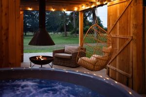 a hot tub on a patio with a chair and a fire pit at Bainton Burrows by Wigwam Holidays in Great Driffield