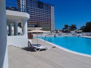 a swimming pool with a lounge chair and an umbrella at Ocean View Deluxe Studio with Sunset Balcony and Pool Playa Paraiso in Playa Paraiso