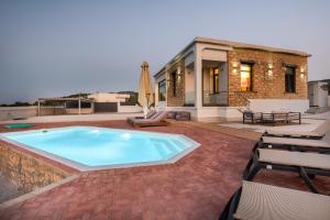 a swimming pool in a patio with chairs and a house at Summer & Sun in Vathí