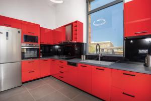 a kitchen with red cabinets and a large window at Summer & Sun in Vathí