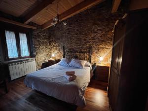 a bedroom with a large bed in a stone wall at El Rincón de la Rosa in Brugos de Fenar