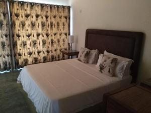 a bedroom with a large white bed with a window at Lodge Kapembawé in Benguela