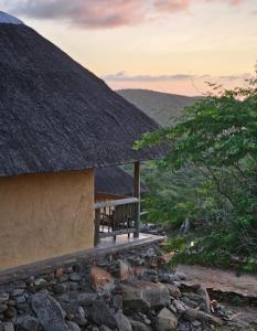 a hut with a thatched roof with a stone wall at Lodge Kapembawé in Benguela