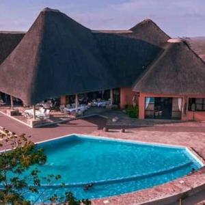 a swimming pool in front of a building with a roof at Lodge Kapembawé in Benguela