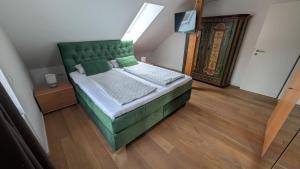 a green bed in a room with a wooden floor at Ferienwohnung Malbrich in Gräfenberg