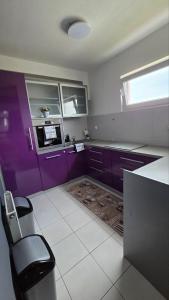 a kitchen with purple cabinets and a chair in it at DenVigo in Čakovec