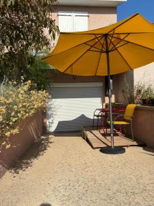 a yellow umbrella sitting next to a garage at Au Petit Paradis in Balan