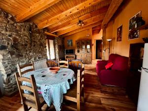 a dining room with a table and a red couch at El Rincón de la Rosa in Brugos de Fenar