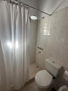 a bathroom with a toilet and a shower curtain at Solymar Alojamiento in Puerto Madryn