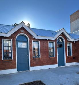a red brick building with two blue doors at Solymar Alojamiento in Puerto Madryn