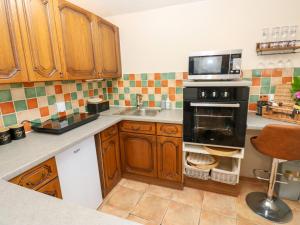 a kitchen with a stove and a sink and a microwave at Arch Mews Cottage in Barnard Castle