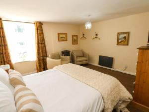 a bedroom with a white bed and a chair at Arch Mews Cottage in Barnard Castle