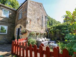 a brick house with a wooden fence in front of it at Arch Mews Cottage in Barnard Castle