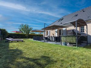 a patio with a bench and umbrellas in a yard at Chambre d'hôtes près du Château in Sully-sur-Loire