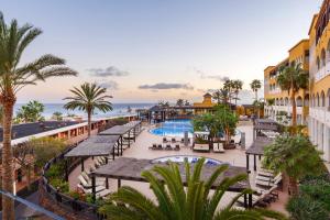a resort with a pool and tables and palm trees at Occidental Jandía Royal Level - Adults Only in Morro del Jable