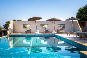 a pool with chairs and umbrellas next to a house at Villa de luxe Sakina in Essaouira