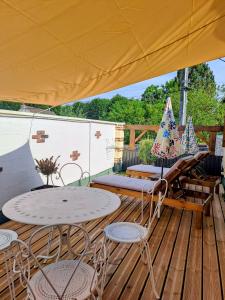a patio with tables and chairs on a wooden deck at le patio de la Cavée " havre de paix" in Verderonne
