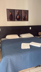 a blue bed with two towels on top of it at Hotel AD Cassilândia in Cassilândia