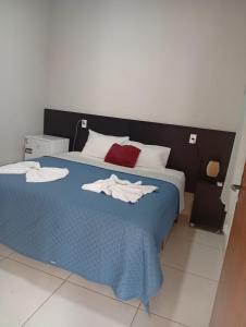 a bedroom with a blue bed with towels on it at Hotel AD Cassilândia in Cassilândia