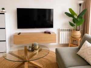 a living room with a tv and a glass table at Casa Lilo - Renovated 2-Bed Apartment with Pool View - La Torre Golf Resort in Torre-Pacheco