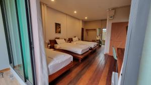 a room with three beds and a window at Piney Stay ไพนี่สเตย์ เขาค้อ in Campson