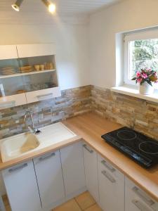 a kitchen with white cabinets and a sink and a window at Elbblick-kleine-Wohnung-mit-Terrasse in Gollhofen +3 photos