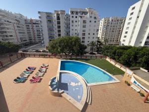 a swimming pool with lounge chairs in a city at Rabelo C in Armação de Pêra