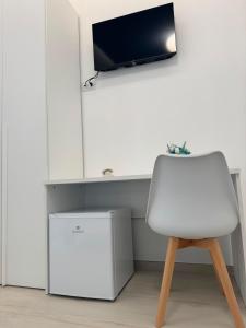 a white chair in a room with a tv on a wall at B&B La Perla di Praia in Praia a Mare