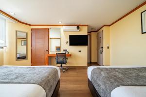 ein Hotelzimmer mit zwei Betten und einem Schreibtisch in der Unterkunft Hotel Abastos Plaza in Mexiko-Stadt