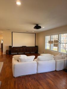 a room with two white couches in front of a screen at Steps from beach with open fire pit in Gulfport