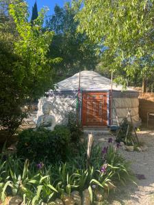 a yurt with a statue in the middle of a garden at Yourte piscine jacuzzi in Gréoux-les-Bains