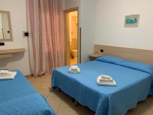 two beds in a hotel room with towels on them at B&B Florida sul mare via faro 30 in Capo Rizzuto