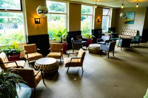 a waiting room with chairs and tables and windows at Budget Hostel De Elderschans in Aardenburg
