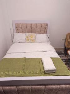 a large bed with two pillows and a green blanket at Gweth Haven Homes in Nakuru
