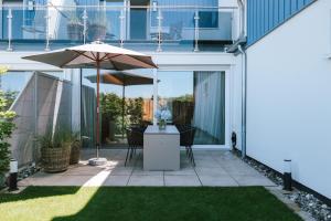 a patio with a table and an umbrella at Sünn un See - Weststrand-Blick mit Sauna in Ahrenshoop